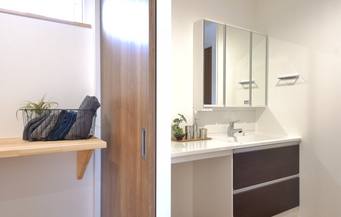 玄関からホール、洗面室、洗面脱衣室、UBへと一直線につながる間取りで、帰宅後の手洗い・入浴・身支度が流れるように行えるスムーズな動線設計。家族それぞれの動きが重なりにくく、日々の生活がとても快適になります。洗面室と洗面脱衣室には、温かみを感じる“コルクタイル”を床に採用。桧の無垢床とは雰囲気が異なり、良いアクセントになっています。