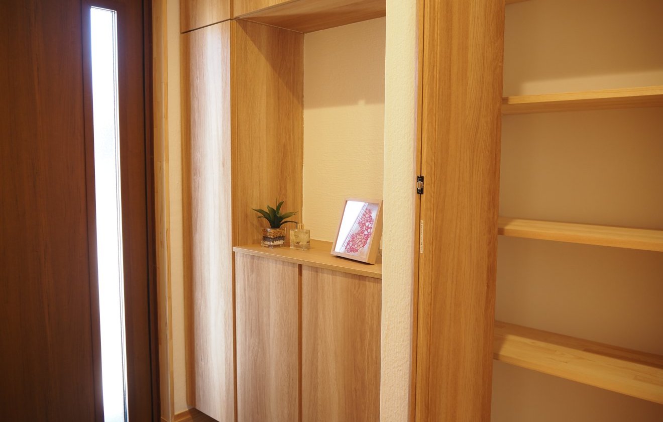 玄関を入ってすぐの場所に設けた収納スペースは、大容量ながら動線を邪魔しない配置。靴や小物をさっとしまえるため、玄関まわりをいつも整った状態に保てます。床には桧の無垢材を使用し、足元からやさしいぬくもりを感じられる空間に。天井と壁を包む漆喰が空気を澄ませ、住まいの第一歩にふさわしい、穏やかで清潔感あふれるホールが広がります。